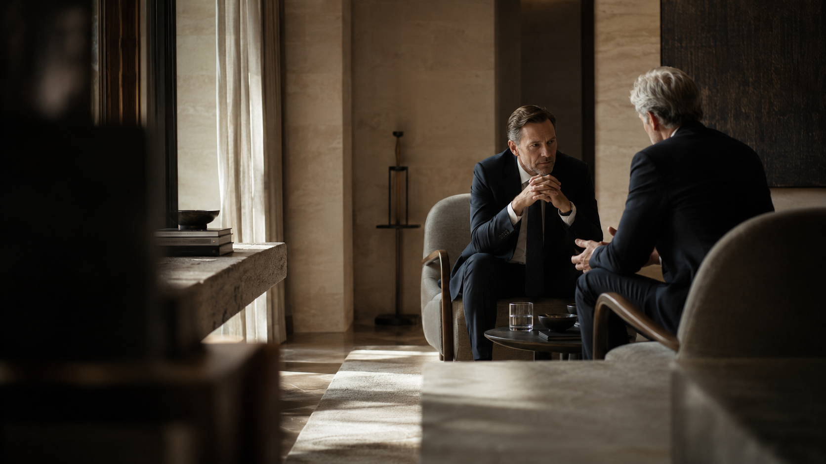 Deux dirigeants en conversation à deux, assis face à face dans un salon feutré.