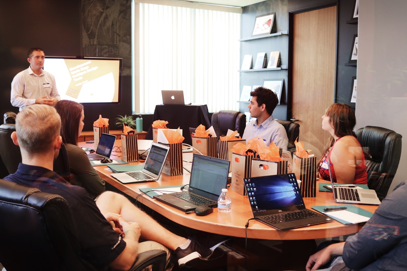 A working session around a meeting table, laptops open.